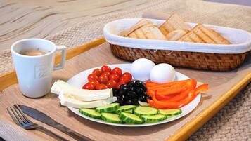 Una bandeja con un plato de comida que incluye tomates, pepinos, queso, huevos, aceitunas y pan, junto con una taza de café.