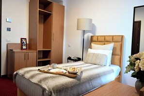 A hotel room with a bed, a bedside table, a lamp, a wardrobe, and a tray with breakfast items. - Bucharest Airport Hotel (Otopeni)