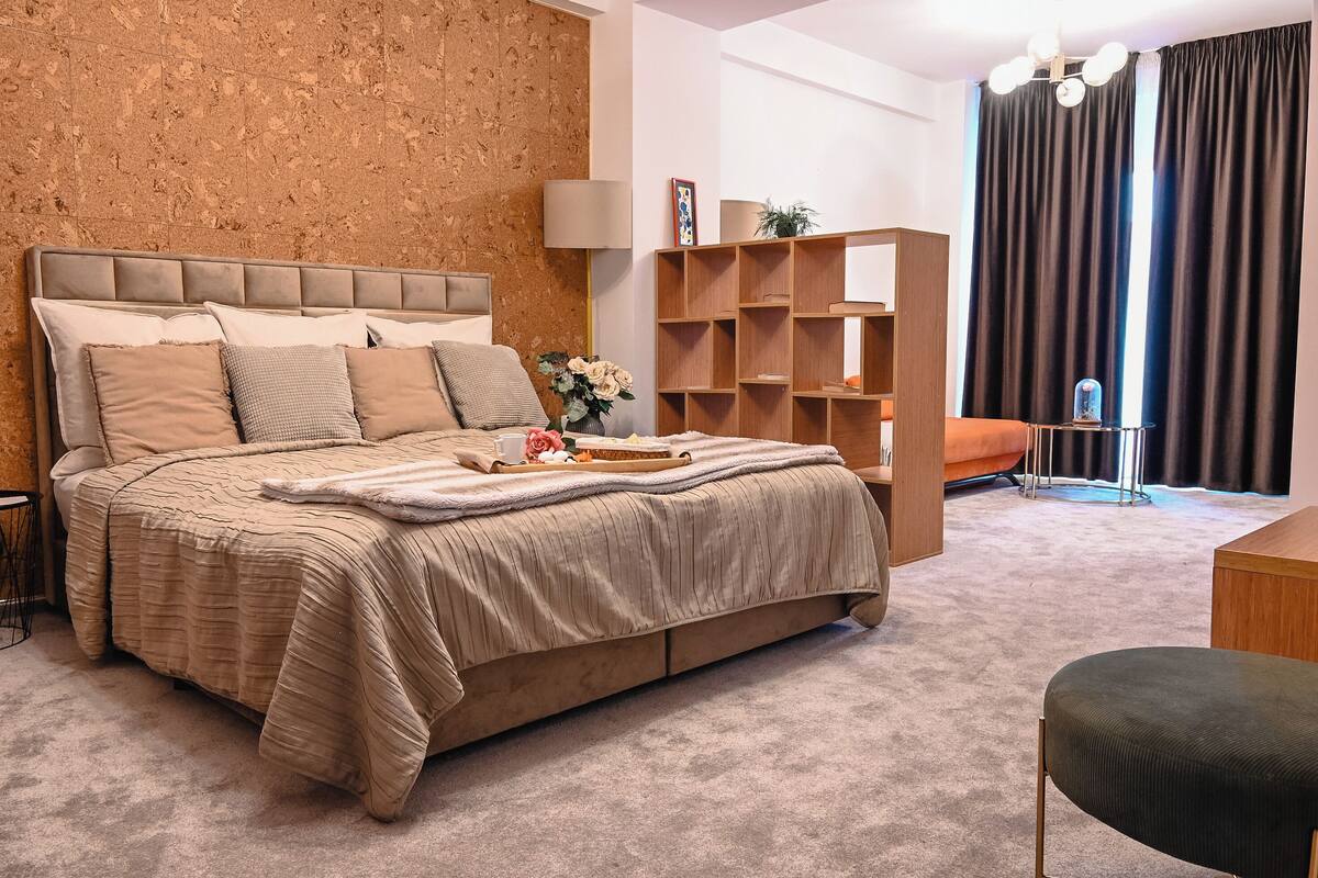 A bedroom with a large bed, a wooden bookshelf, a desk, and a chair.