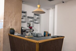 Una zona de recepción con mostrador de madera, máquina de café y lámpara colgante moderna.