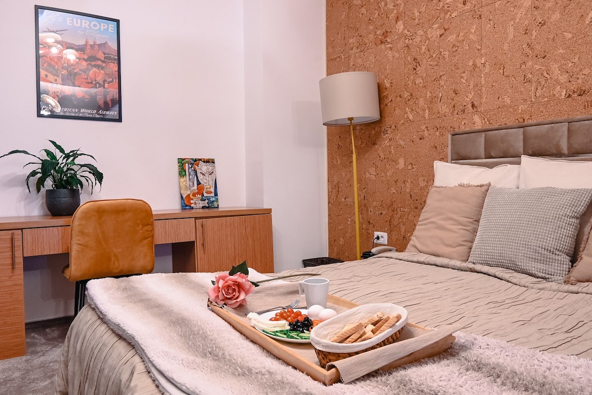 A neatly arranged bedroom with a bed, bedside table, and a desk area.