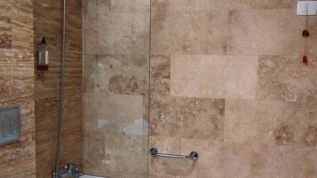 A bathroom with a glass-enclosed shower, a white bathtub, and a toilet.