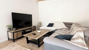 En moderne stue med et fladskærms-tv, en sofa, et sofabord og et træloft.