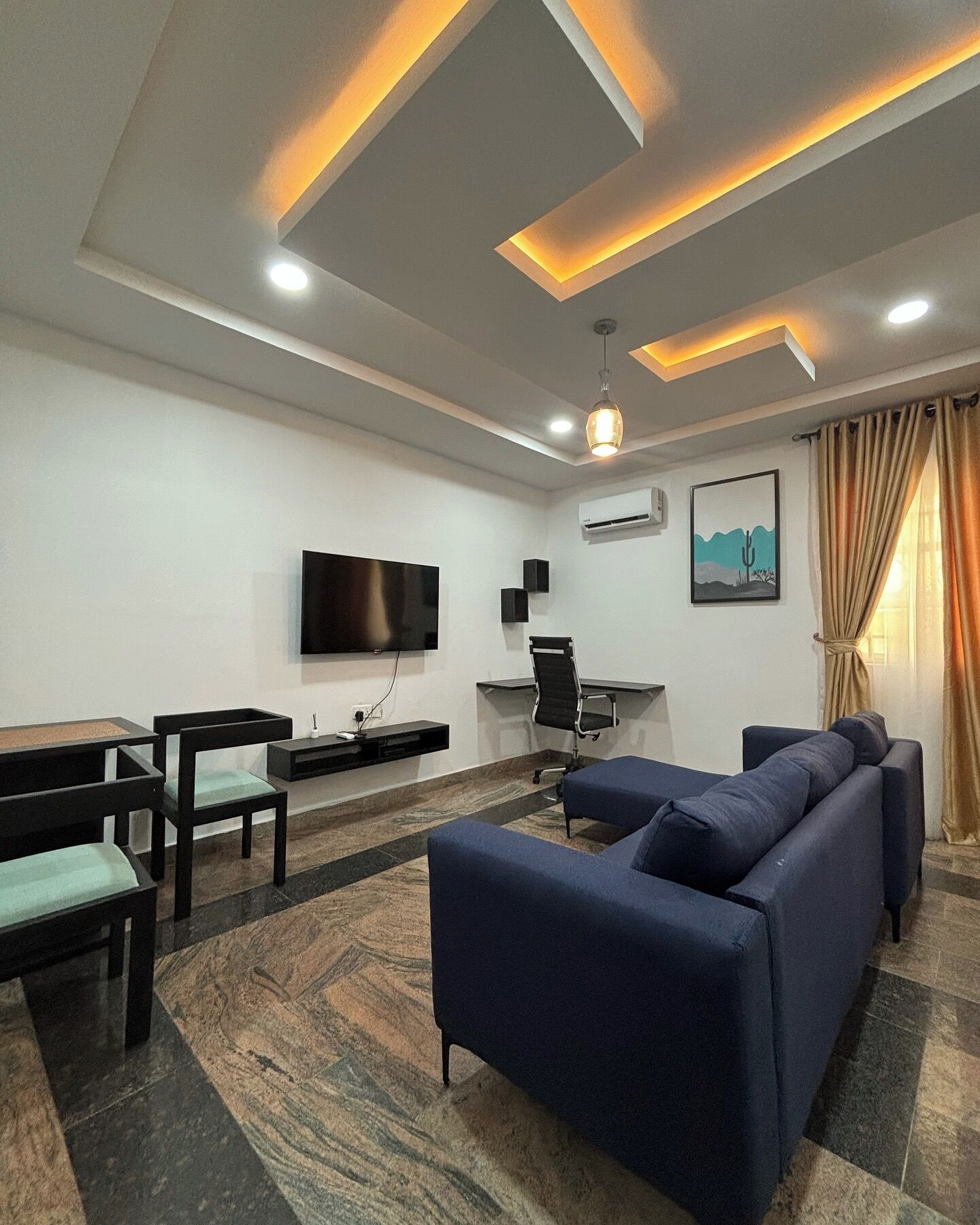 A modern living room with a sofa, chairs, a TV, and a desk.