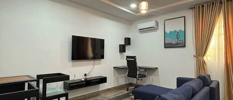 Una sala de estar moderna con un sofá, sillones, un televisor y un escritorio.