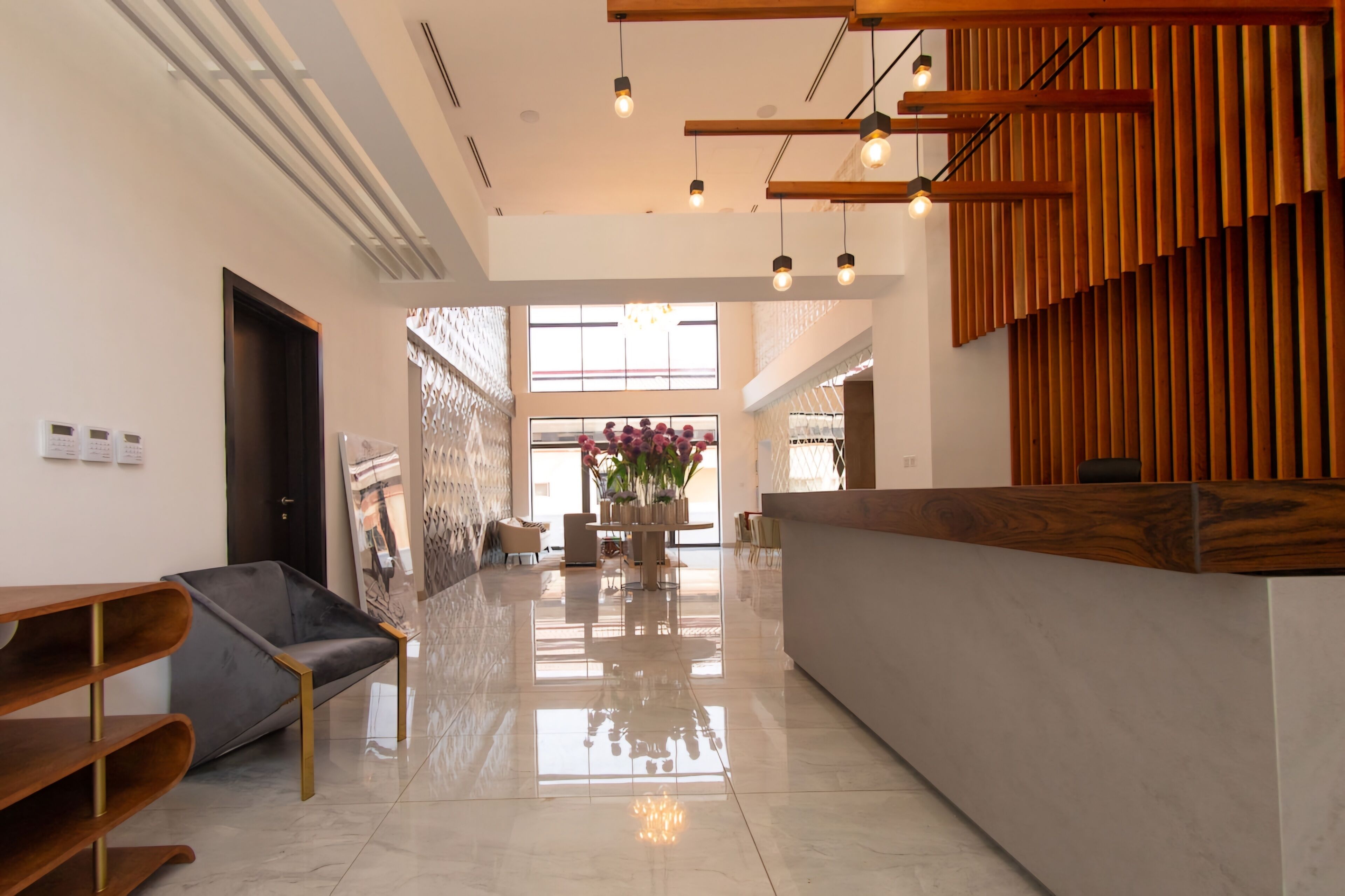 A modern lobby with a reception desk, seating area, and a large window providing natural light.