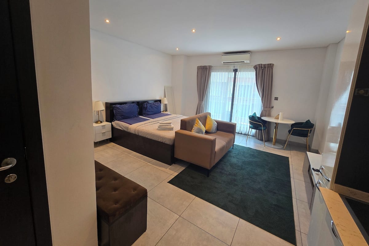 A hotel room with a bed, a sofa, a small table, and a chair.
