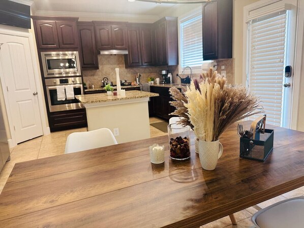 A kitchen with dark wooden cabinets, stainless steel appliances, and a wooden island with decorative items.