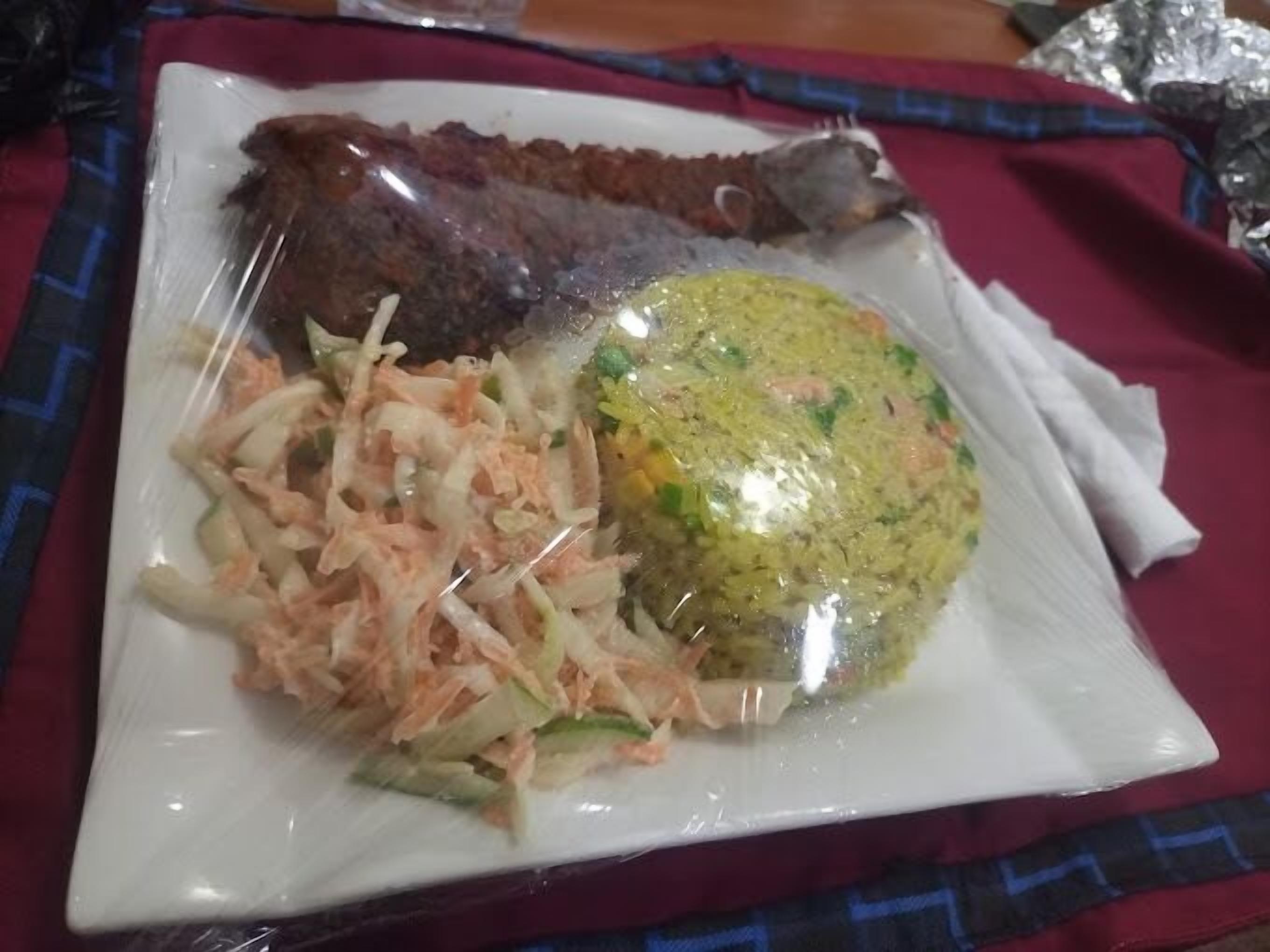 A plate with a fish, rice, and coleslaw.