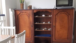 Una cocina con un armario de madera, un microondas y una silla.