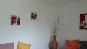 Una sala de estar moderna con dos sofás, una mesa de centro de madera y un florero con ramas.