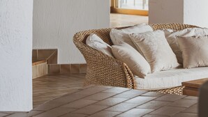 A cozy living room with a wicker sofa, a wooden coffee table, and a view through an arched doorway to a dining area. - Luxury Villa with private beach and splendid pool on Sea Front (Porto-Vecchio)