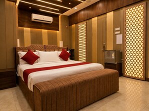Ein Hotelzimmer mit einem großen Bett, einer Bank, einem Kleiderschrank und einer Minibar.