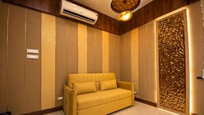 A room with a sofa, an air conditioning unit, a textured wall, and a decorative panel.