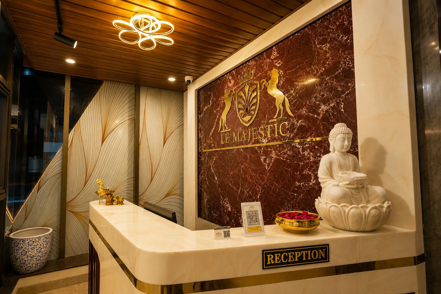A reception desk with a marble wall, a Buddha statue, and a sign reading 'THE MAJESTIC'.