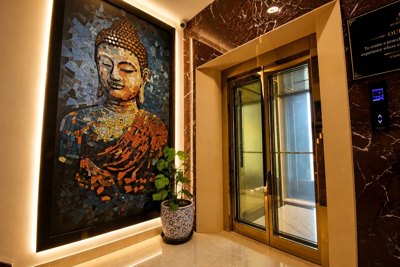 A mosaic Buddha artwork, a potted plant, and a glass elevator door in a lobby.