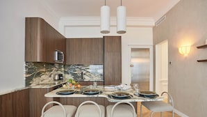 A modern kitchen with a marble countertop, stainless steel appliances, and a bar area with stools.