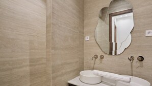 A modern bathroom with a marble vanity, a round sink, and a wall-mounted mirror.