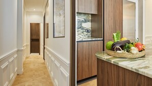 A hallway with a wooden door and a kitchen counter with a fruit basket.