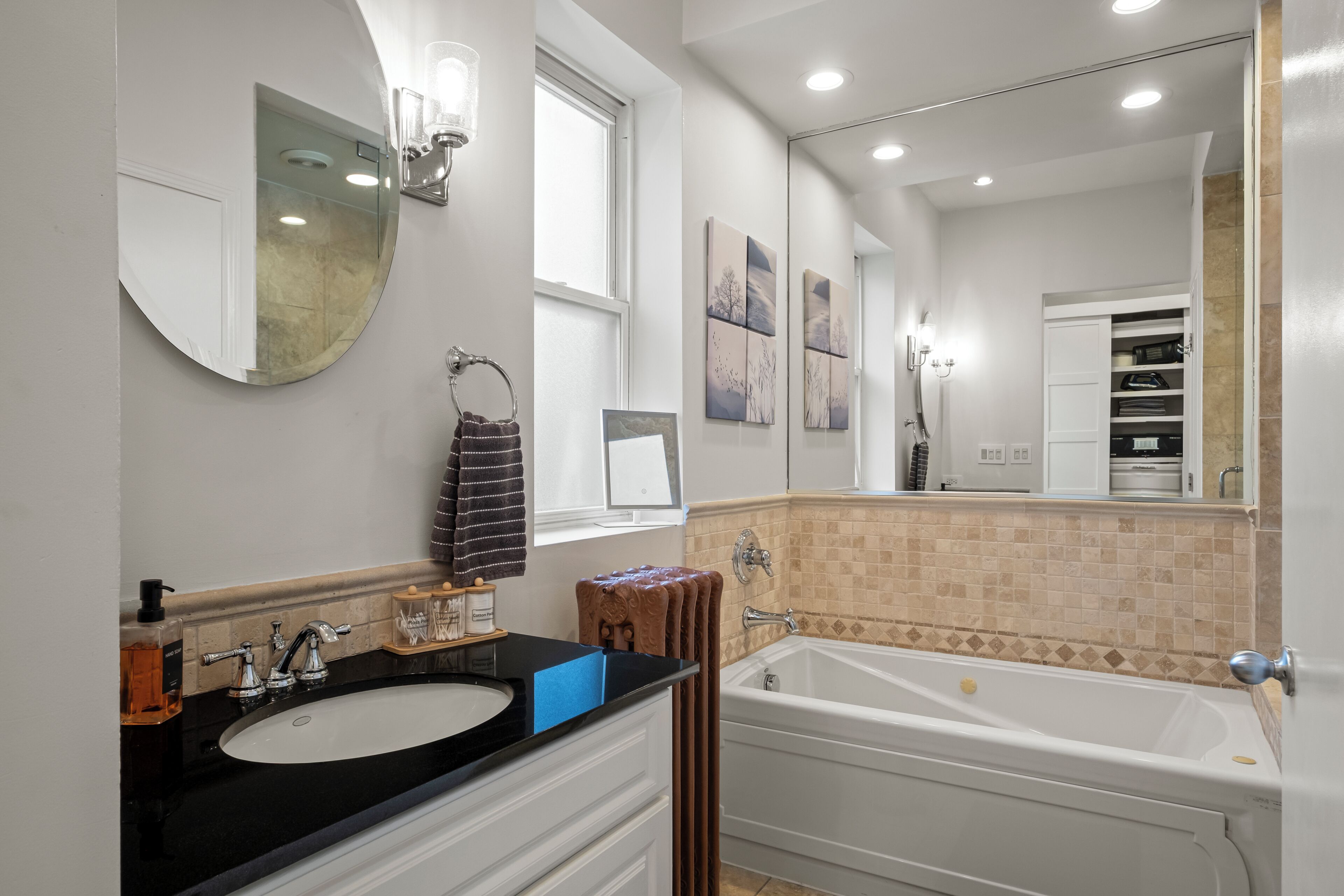 Une salle de bain avec un lavabo, un miroir, une baignoire et des murs carrelés.