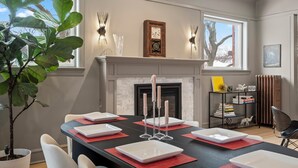 A dining area with a fireplace, a potted plant, and a bookshelf. - This 2 bedroom 2 bathroom elegantly furnished home is ready for all your needs.  Featuring a primary bedroom suite, TV room, dining room, and additional sitting areas. (Chicago)