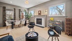 A modern living room with a fireplace, dining area, and large windows. - This 2 bedroom 2 bathroom elegantly furnished home is ready for all your needs.  Featuring a primary bedroom suite, TV room, dining room, and additional sitting areas. (Chicago)