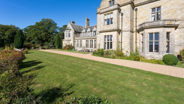 A large stone building with multiple windows and a well-maintained lawn.