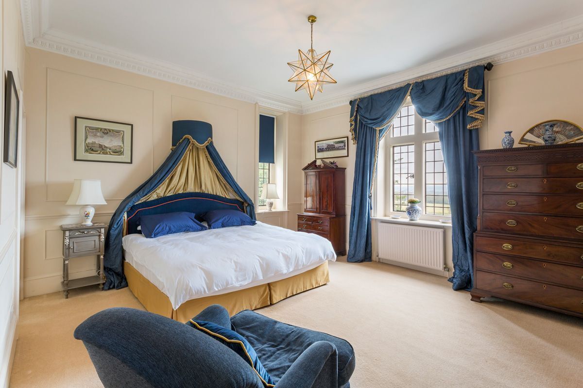 Une chambre à coucher avec un lit à baldaquin, une commode en bois et une table de chevet avec une lampe.