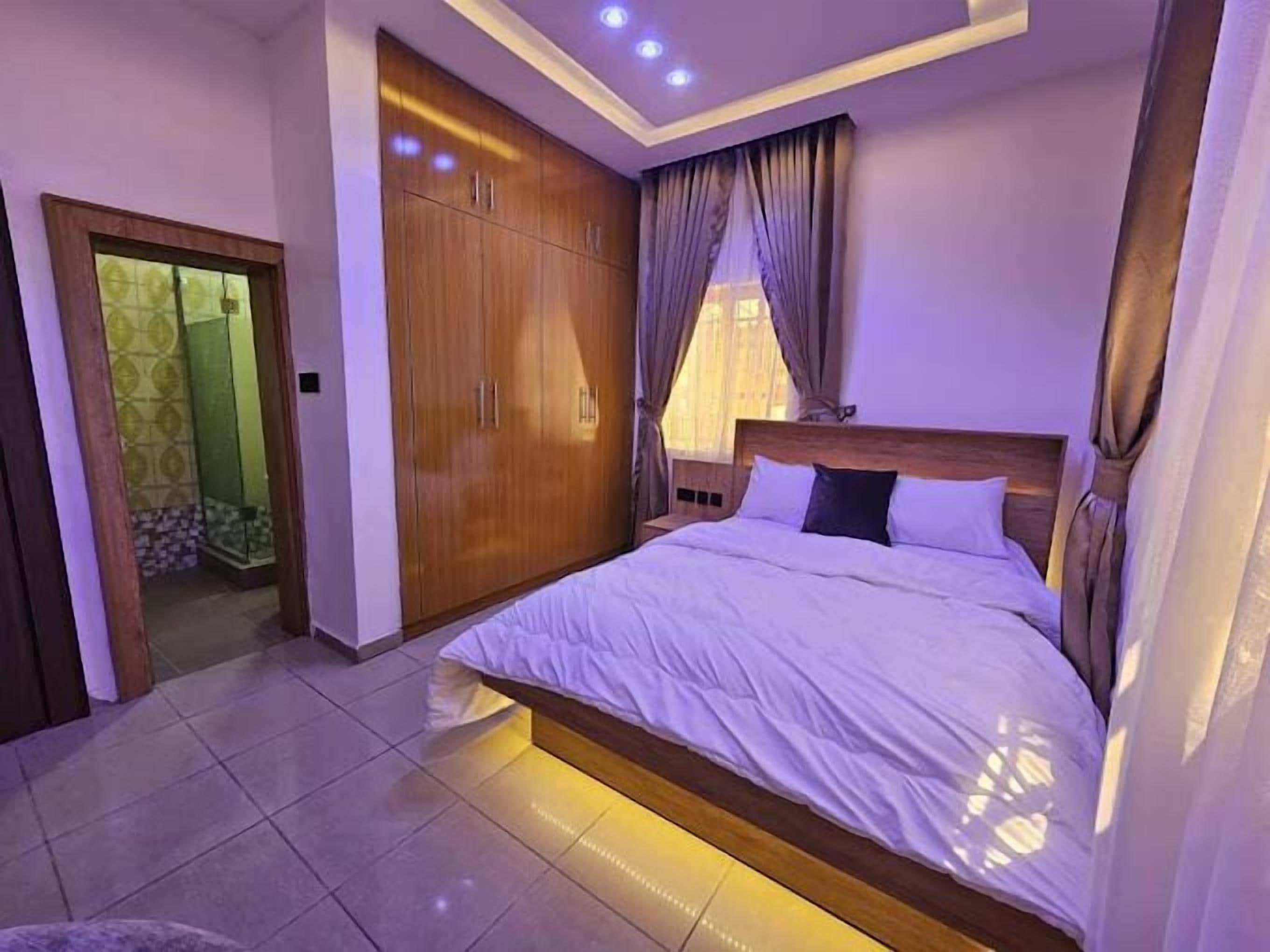 Un dormitorio con una cama grande, armario de madera y zona de ducha.