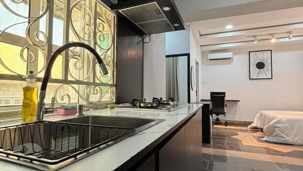 Una cocina moderna con un grifo negro, electrodomésticos de acero inoxidable y una ventana con detalles de metal decorativo.