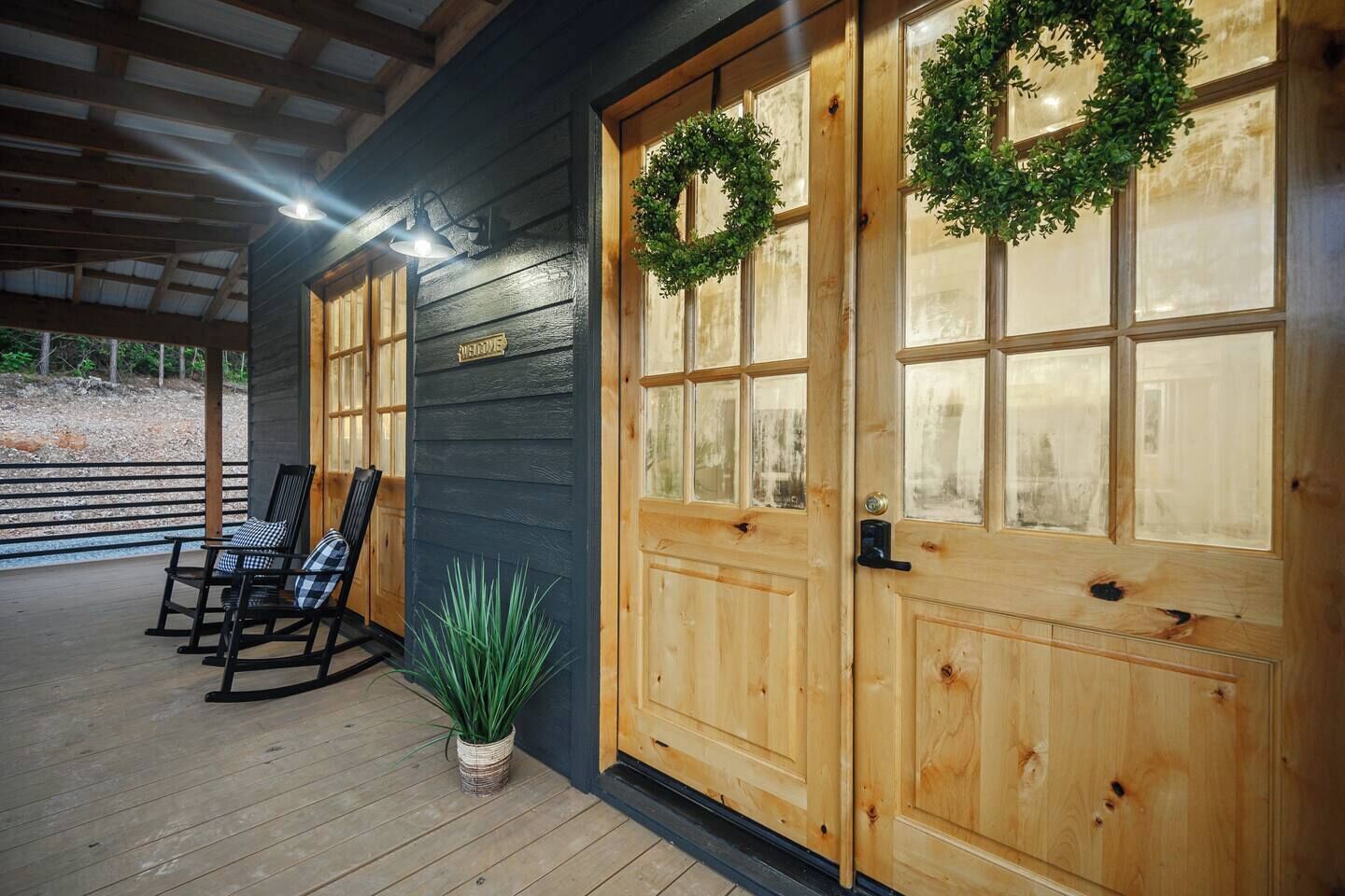 Eine hölzerne Veranda mit Schaukelstühlen und einem Blumentopf.