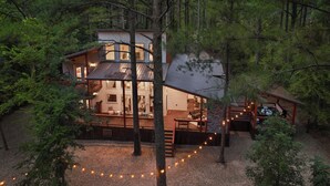 Un chalet à plusieurs niveaux avec une terrasse, entouré d’arbres.