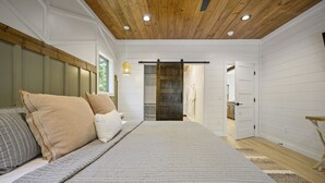 Une chambre à coucher avec un lit, un plafond en bois et une porte coulissante donnant sur une autre pièce.