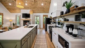 Una cocina moderna con una isla grande, techo de madera y electrodomésticos integrados.