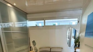 Une chambre à coucher moderne avec un grand lit, une table de chevet, un miroir et une vue sur l’extérieur.