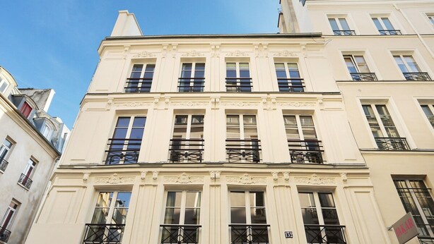 A multi-story building with a classic architectural style, featuring symmetrical windows and decorative moldings. - Apartement Center of Paris (Paris)