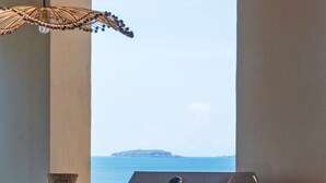 Una cocina con un ventanal grande con vistas al mar, una parrilla y un comedor con sillas y mesa.