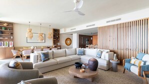 Una sala de estar moderna con un sofá modular, una mesa de centro y un comedor con una mesa y sillas de madera.