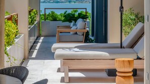 Un área de estar moderna al aire libre con vista al mar, techo de madera y un gran paraguas.