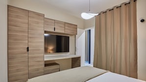A bedroom with a bed, a TV mounted on a wooden cabinet, and a curtain on the window. - Apartment Center of Paris (Paris)