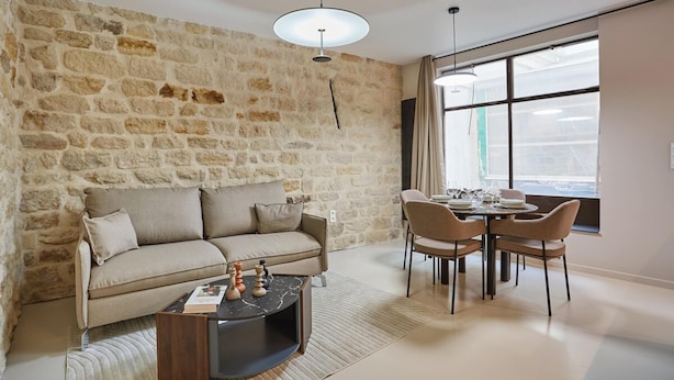 A living room with a stone wall, a sofa, a coffee table, and a dining area with chairs and a table. - Apartment Center of Paris (Paris)