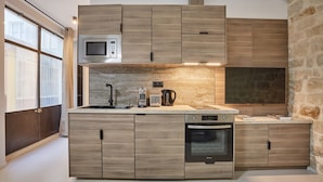 A modern kitchen with wooden cabinets, a built-in microwave, a coffee maker, and an oven. - Apartment Center of Paris (Paris)