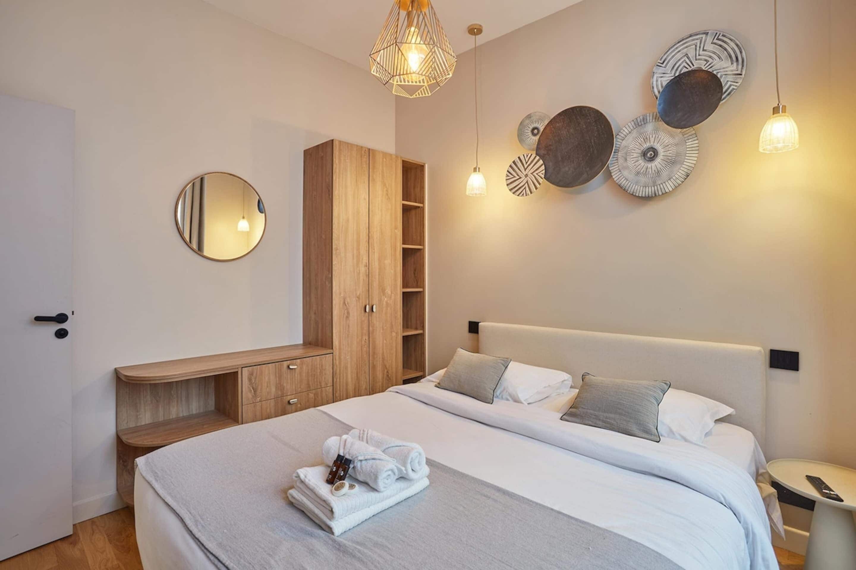 A modern bedroom with a bed, bedside tables, a wardrobe, and wall decorations.