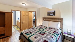 Een slaapkamer met een groot bed, een houten garderobe en een deur naar een badkamer.