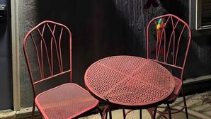 Ein Zimmer mit einer Holzwand, einer Schiffslenken-Dekoration, einem Willkommensschild und zwei roten Metallstühlen.