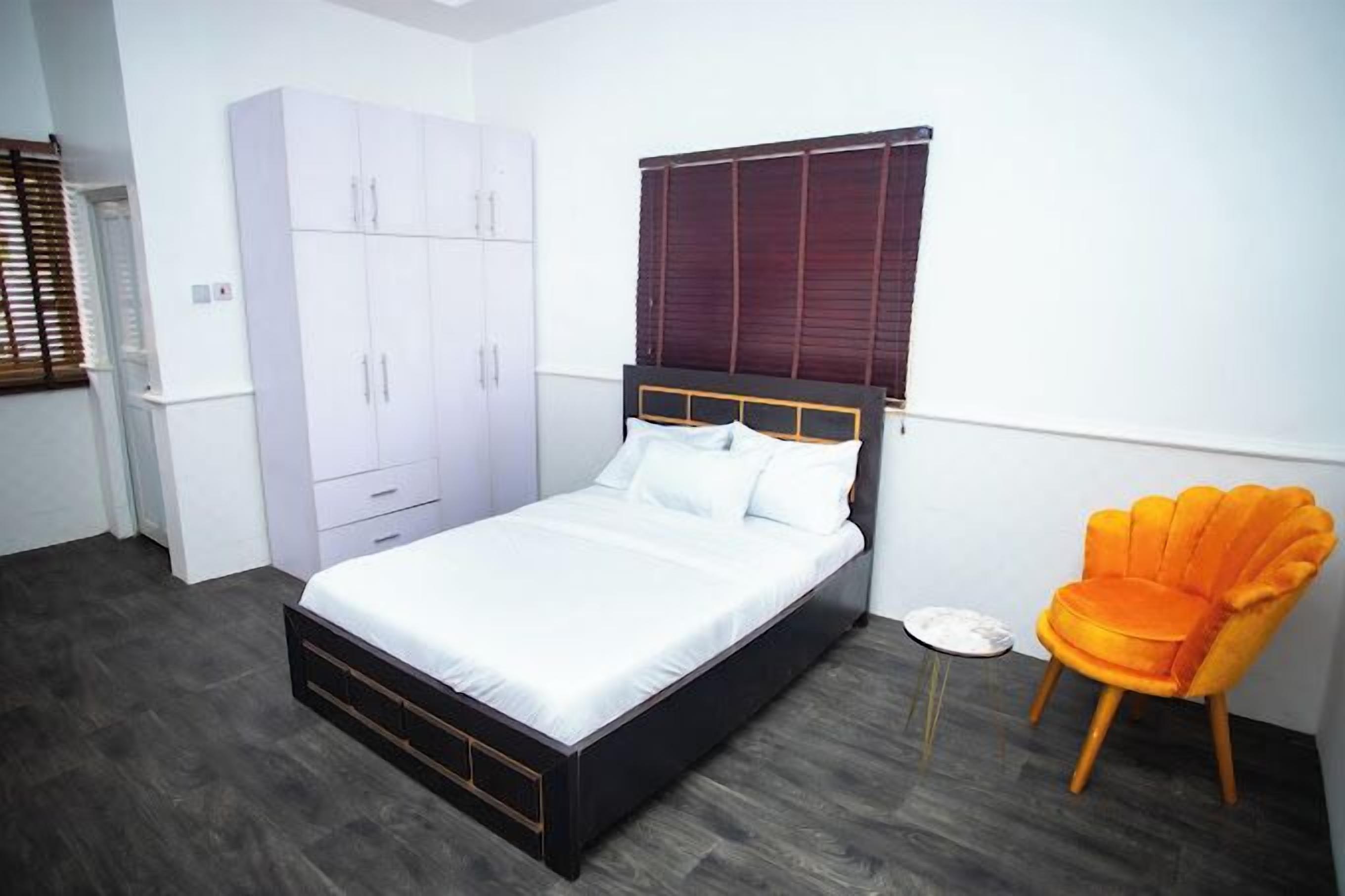 A bedroom with a bed, wardrobe, and a chair.