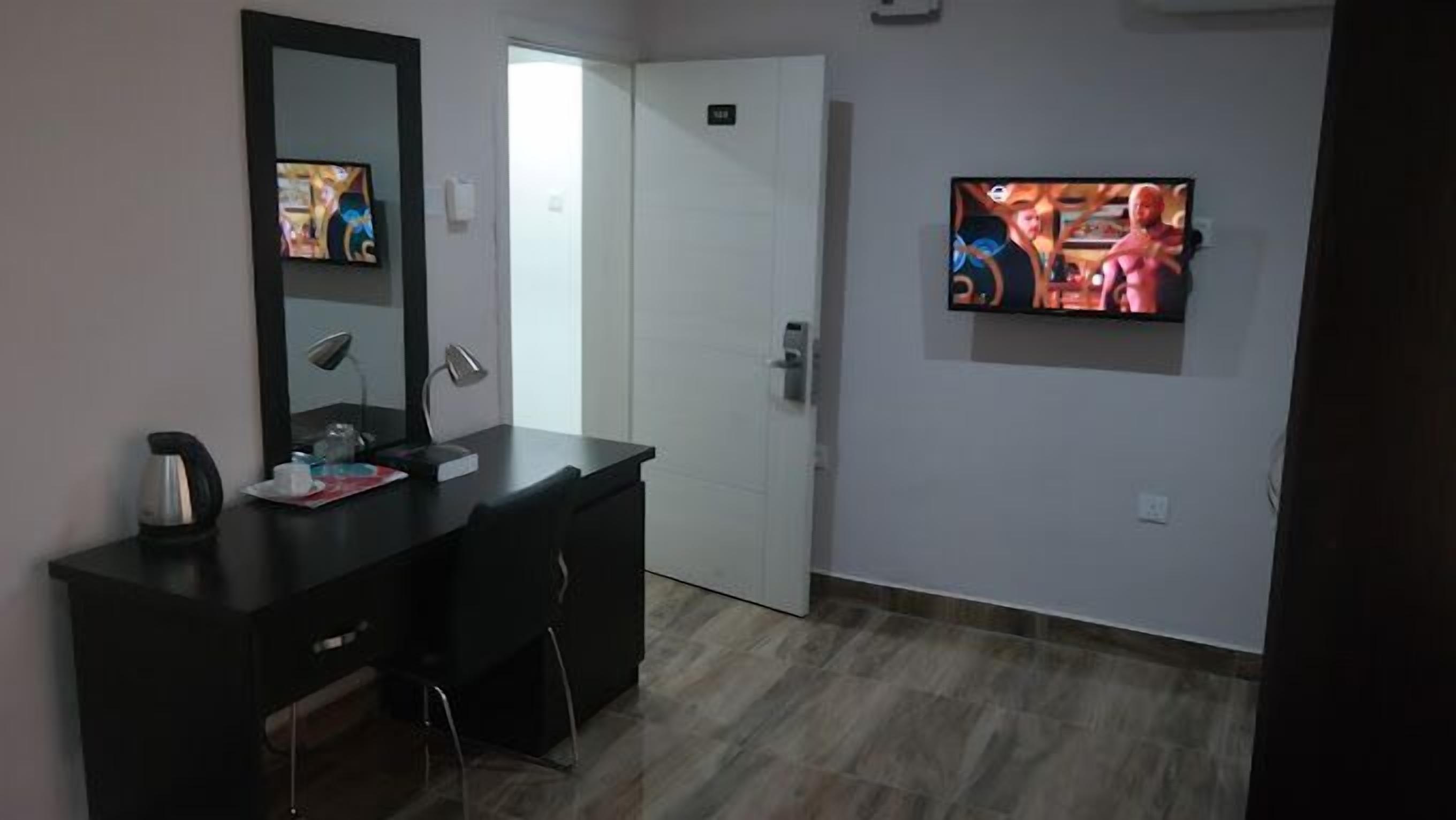Une chambre d’hôtel équipée d’un bureau, d’une chaise, d’une télévision et d’une porte.