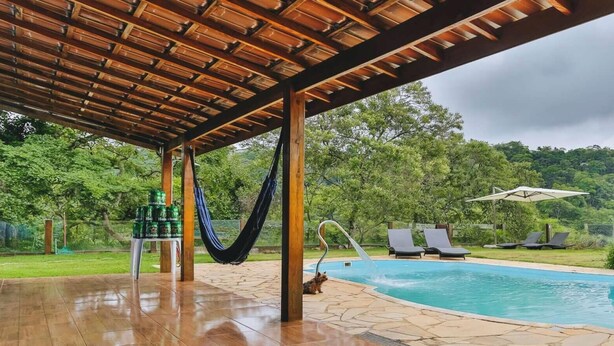 A covered outdoor area with a pool, lounge chairs, and a hammock.