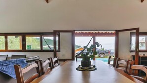 A dining area with a long table, chairs, and a vase with green plants.