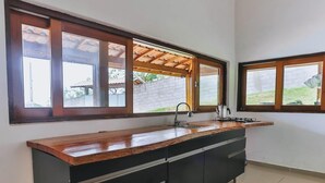 A kitchen with a wooden countertop, a sink, and a window with a view of the outdoors.